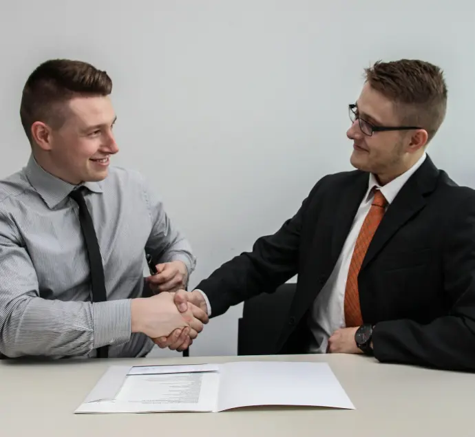two men facing each other while shake hands and smiling
